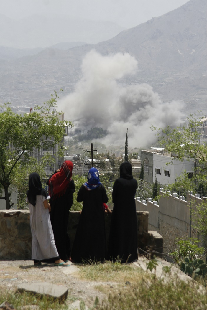 Yemen, Taiz, Jahmalia area. Yemeni girls stare at the fumes coming out of the Republican Palace from the rooftop of their house. 06/2015. Anees Mahyoub/ ICRC