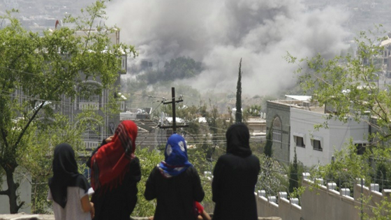 Yemen, Taiz, Jahmalia area. Yemeni girls stare at the fumes coming out of the Republican Palace from the rooftop of their house. 06/2015. Anees Mahyoub/ ICRC