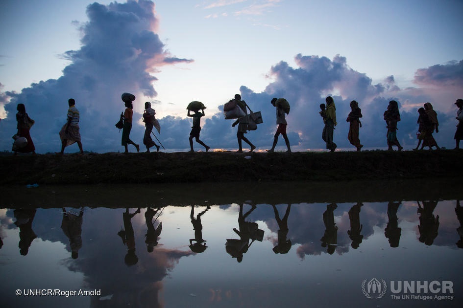Thousands of new Rohingya refugee arrivals cross the border near Anzuman Para village, Palong Khali, Bangladesh. ; As an estimated 500,000 Rohingya sought safety in Bangladesh between late-August and October 2017, UNHCR worked with the authorities to create a transit centre to prepare for a further influx, as some 11,000 people crossed the border on 9th October. They crossed by land into south-eastern Bangladesh through several points. Many came from the Buthidaung area in Myanmar’s northern Rakhine state. Some said they fled torching and killings. Others said they left in fear ahead of anticipated violence. To reach Bangladesh, they walked for days, many carrying children. They waded through marshland before swimming across the Naf river that divides the two countries. UNHCR worked swiftly to accommodate as many as possible in the camps and settlements in Kutupalong and Balukhali, and provided emergency relief items.