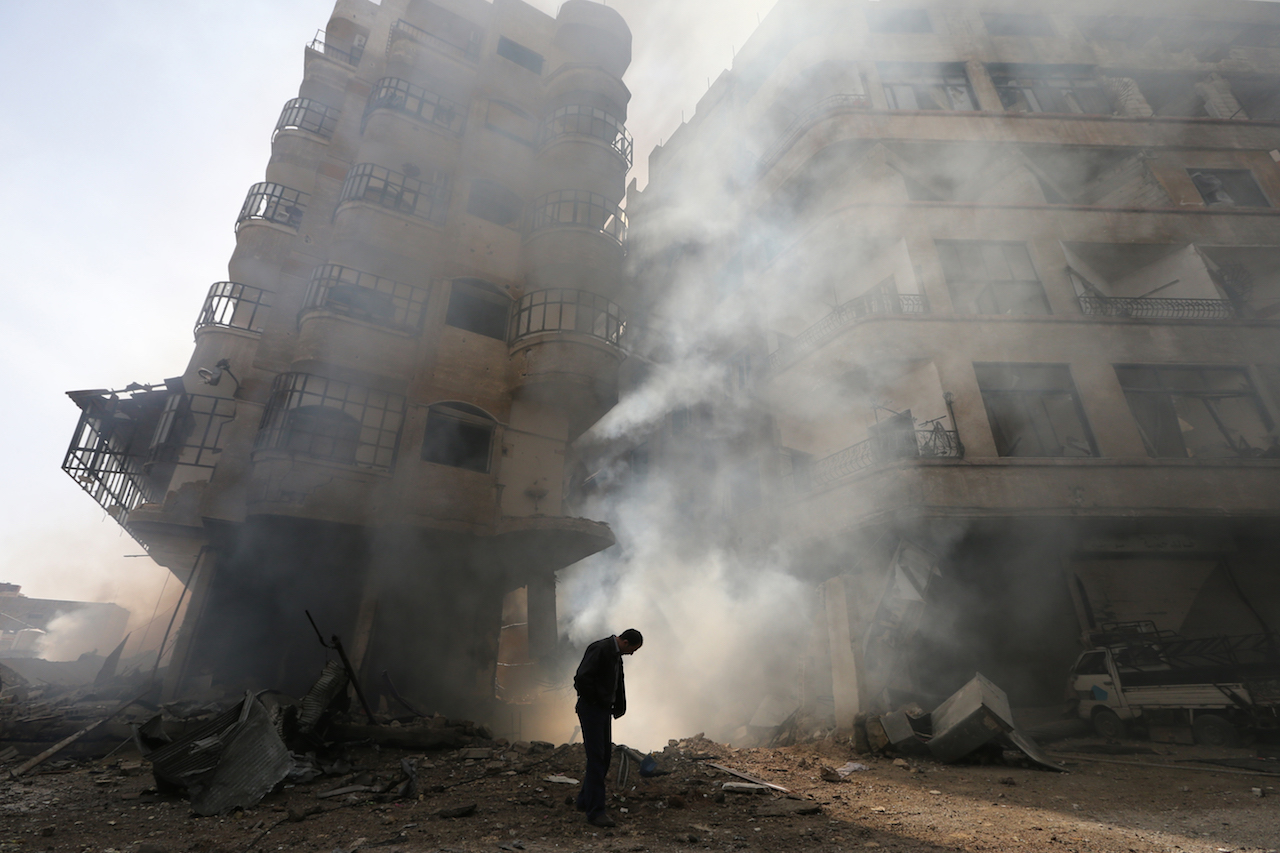 Damascus, Syria. January 27, 2013. A man walks in front of a burning building after a Syrian Air force air strike in Ain Tarma neighbourhood. REUTERS/Goran Tomasevic