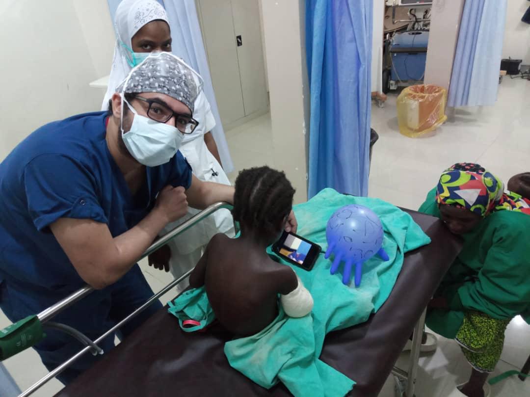 الدكتور أكثم الفرنواني مع طفلة مصابة بعيار ناري في ذراعها قبل دخول غرفة العمليات بمايدوغوري