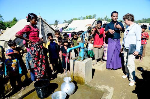 Kamp Thee Chaung, dekat Sittwe, Negara Bagian Rakhine, Myanmar. Pengungsi mengerubuti Patricia Alliot-Guichard, staf ICRC, dan Shithu Tun, staf air dan sanitasi Palang Merah Myanmar, ketika mereka memeriksa tempat persediaan air bersih yang dibangun oleh ICRC dan PMM. © ICRC / Aye Zaw Myo / v-p-mm-e-00146