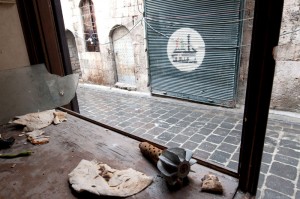 Old city, Aleppo, Part of a mortar bomb lies in the remains of a shop window, its deadly menace contrasting oddly with pieces of life-giving bread.