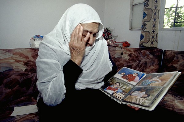דרום לבנון, 1999. קשישה שנאלצה לעזוב את ביתה בוכה לנוכח תמונות של נכדים שהיא חוששת שלעולם לא תזכה לראות שוב.