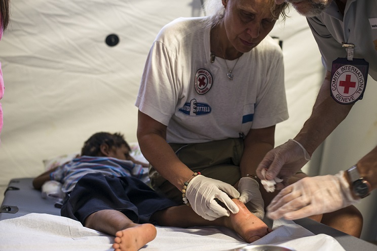 ICRC doctor and nurse perform minor surgery to remove debris from a child's feet.